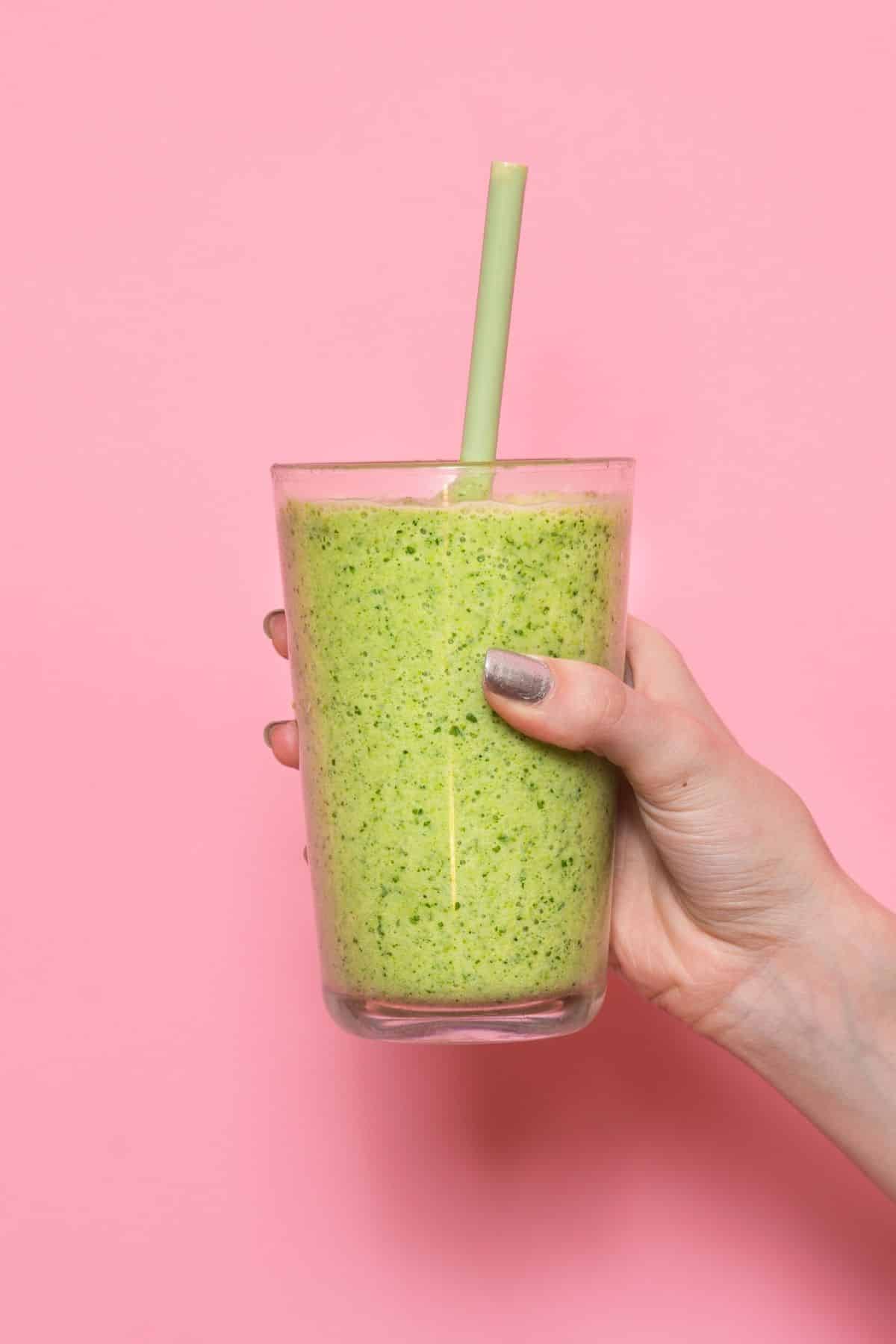 https://www.cleaneatingkitchen.com/wp-content/uploads/2020/10/woman-holding-a-green-smoothie-in-front-of-a-pink-background.jpg